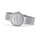 Montre-bracelet minimaliste argentée avec cadran rond et bracelet maille acier, vue de profil.