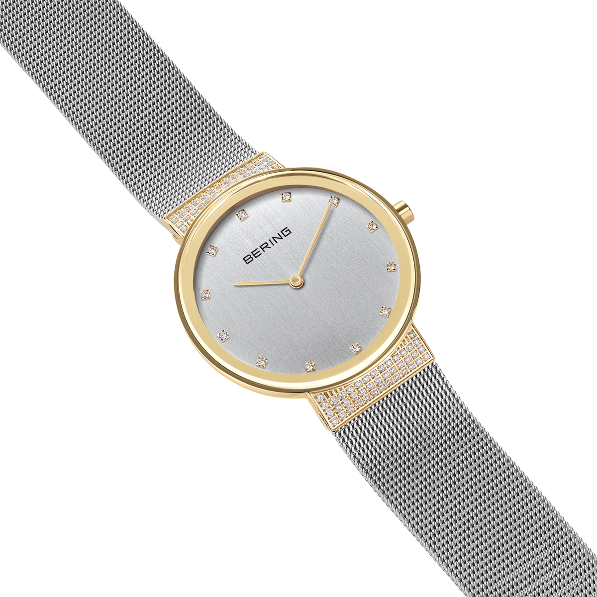 BERING wristwatch with light dial, gold-tone case and mesh bracelet, shown at an angle displaying the side profile.