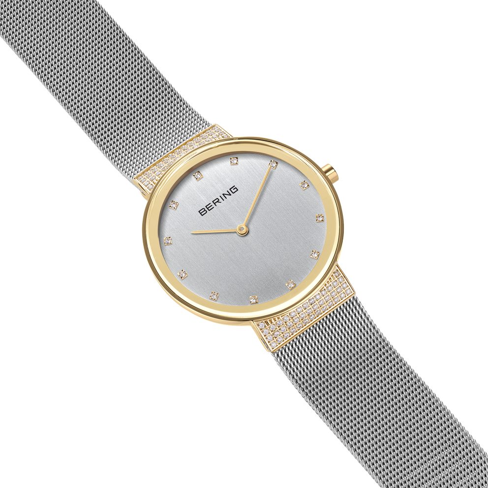 BERING wristwatch with light dial, gold-tone case and mesh bracelet, shown at an angle displaying the side profile.