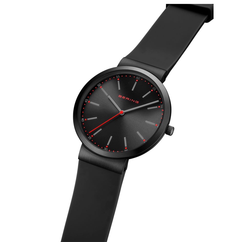 Zwart BERING horloge met minimalistisch wijzerplaat, rode wijzers en zwart bandje, schuin gefotografeerd