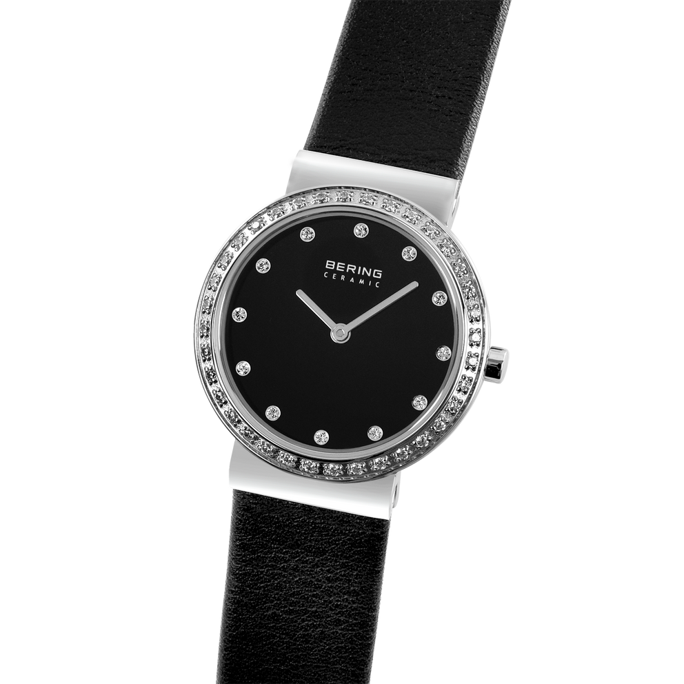 Reloj BERING en muñeca, correa cuero negra drapeada, bisel diamantes y detalle caja visibles