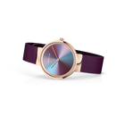 Reloj BERING Anniversary en vista 3/4 con caja oro rosa, esfera iridiscente y correa malla púrpura.