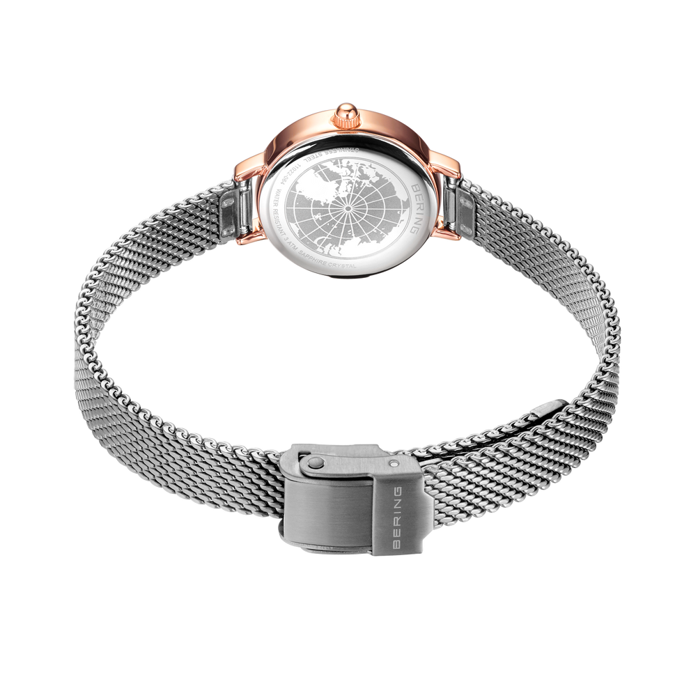 Vista trasera del reloj BERING 11022-064 con caja de oro rosado y pulsera de malla plateada con cierre magnético.