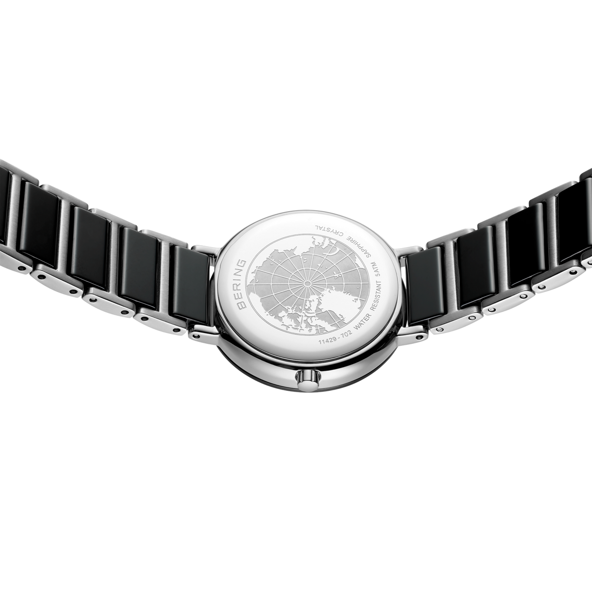 Orologio da polso con quadrante tondo a motivo e cinturino a maglie nere, fotografato dall'alto.