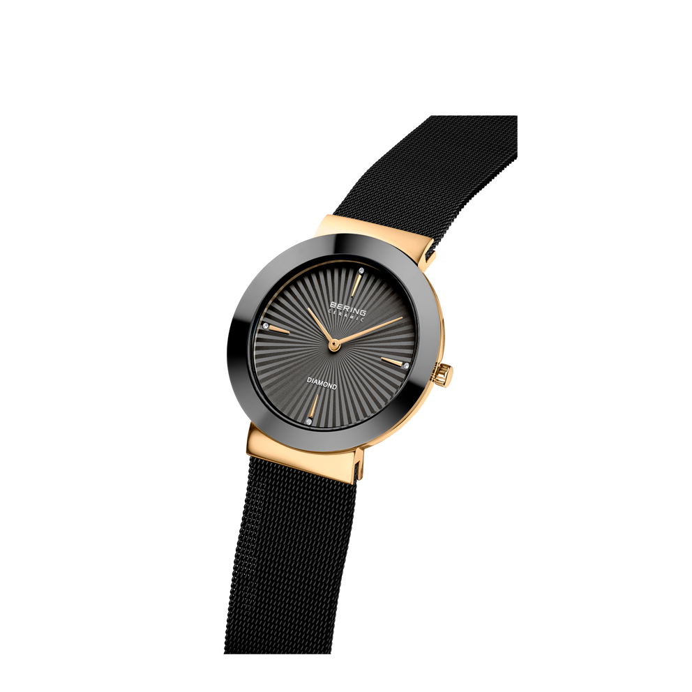 Montre-bracelet à cadran rond noir, boîtier doré et bracelet mesh noir, présentée en angle.