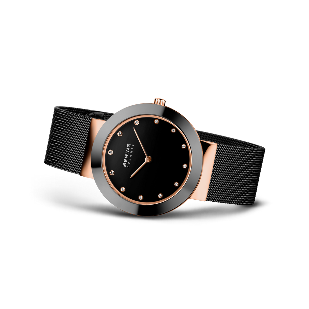 Orologio BERING con quadrante nero, marcatori orari e lancette color oro rosa, cinturino maglia nera, vista tre quarti