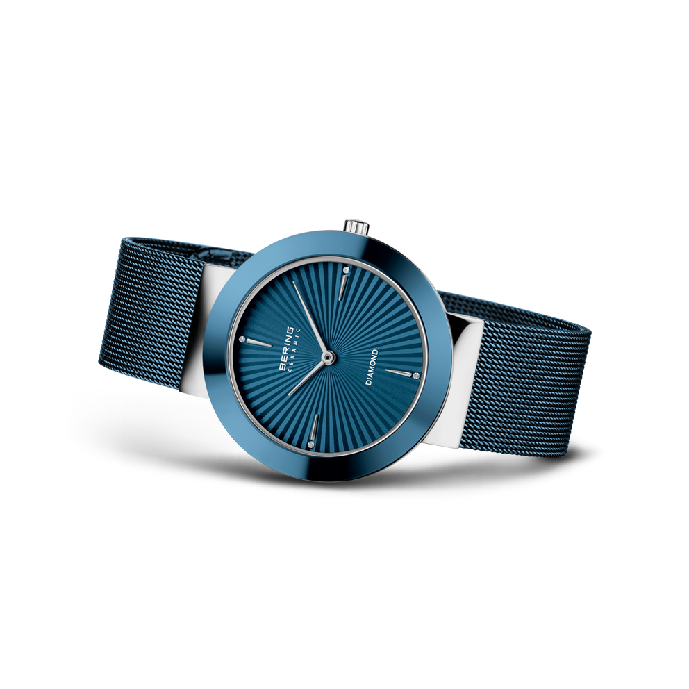 Orologio con quadrante blu con motivo radiale, cassa blu e cinturino in maglia nera, visto da tre quarti.