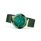 Orologio con quadrante turchese, indici applicati, cassa beige, lunetta turchese e cinturino verde in maglia, vista angolare.