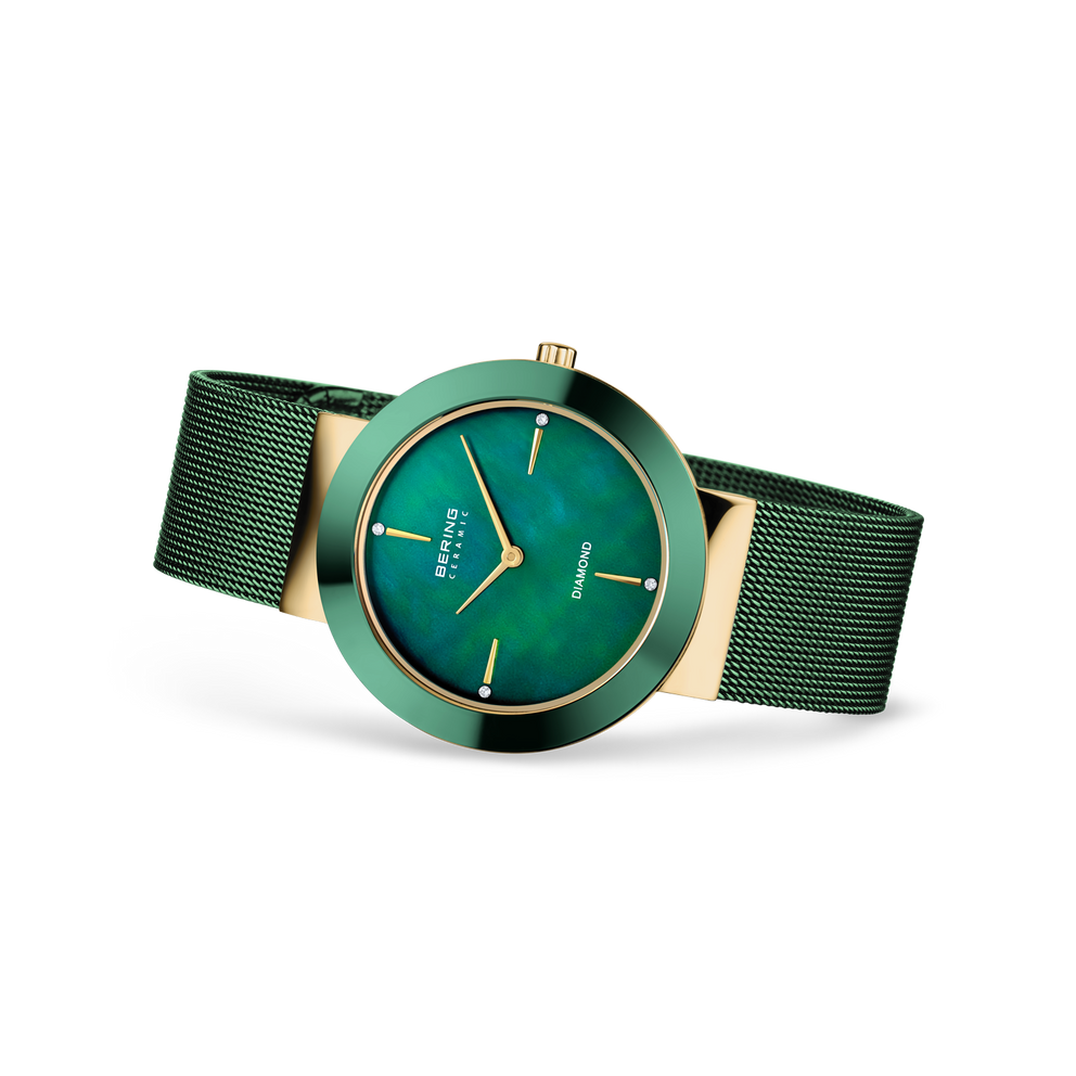 Orologio con quadrante turchese, indici applicati, cassa beige, lunetta turchese e cinturino verde in maglia, vista angolare.