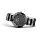 Quadrante rotondo nero con linee radiali e indici minimalisti, bracciale nero e argento segmentato, vista di tre quarti
