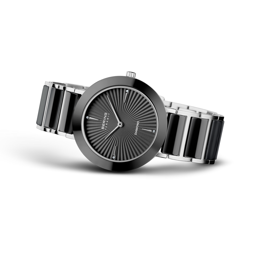 Quadrante rotondo nero con linee radiali e indici minimalisti, bracciale nero e argento segmentato, vista di tre quarti