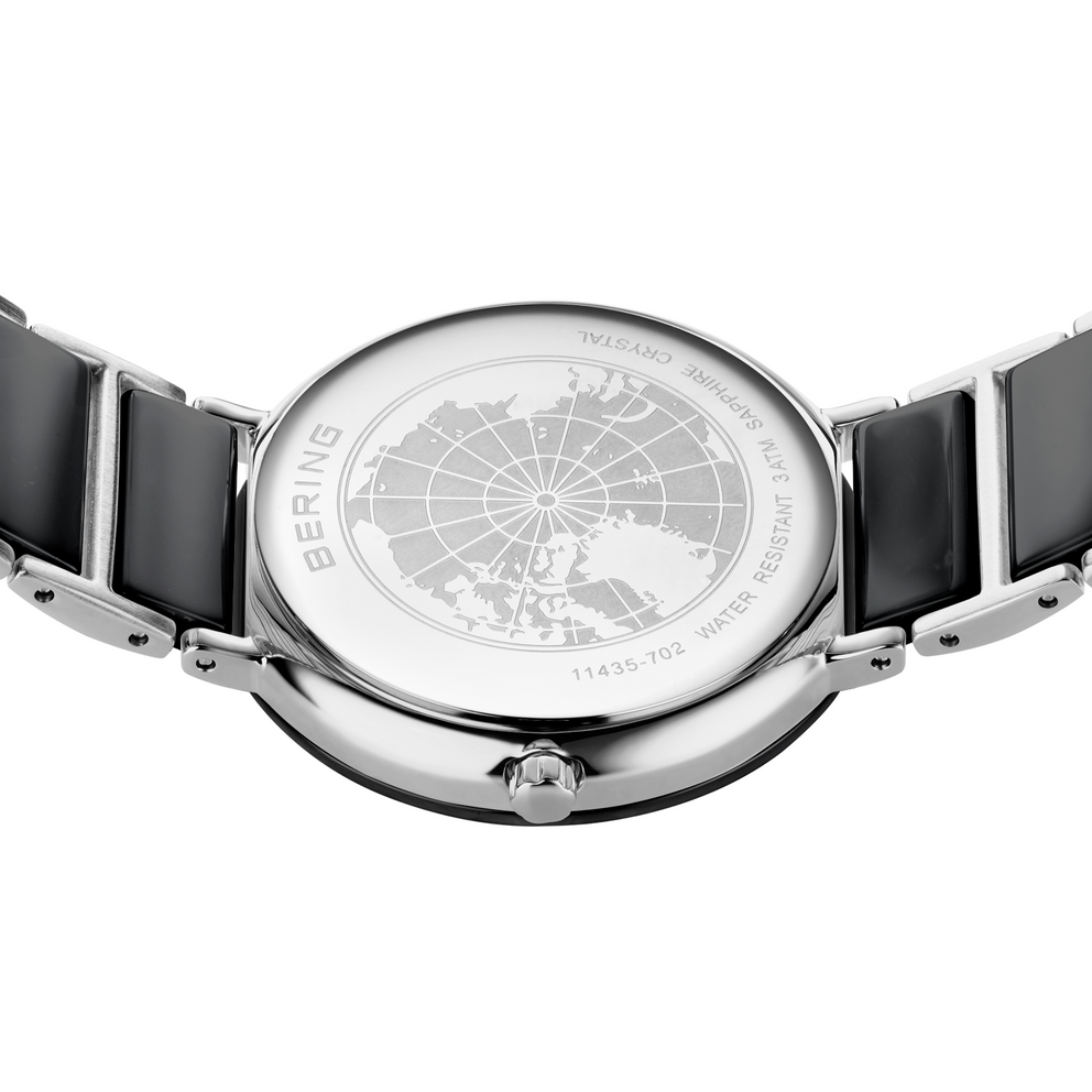 Orologio in acciaio con quadrante a griglia, vista dall'alto, cinturini neri visibili ai lati.
