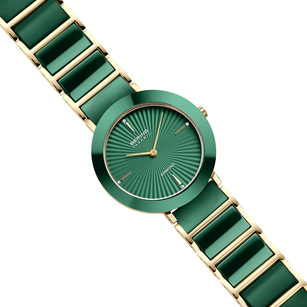 Orologio rotondo verde con quadrante a raggi, lancette dorate e cinturino verde e dorato a maglie.
