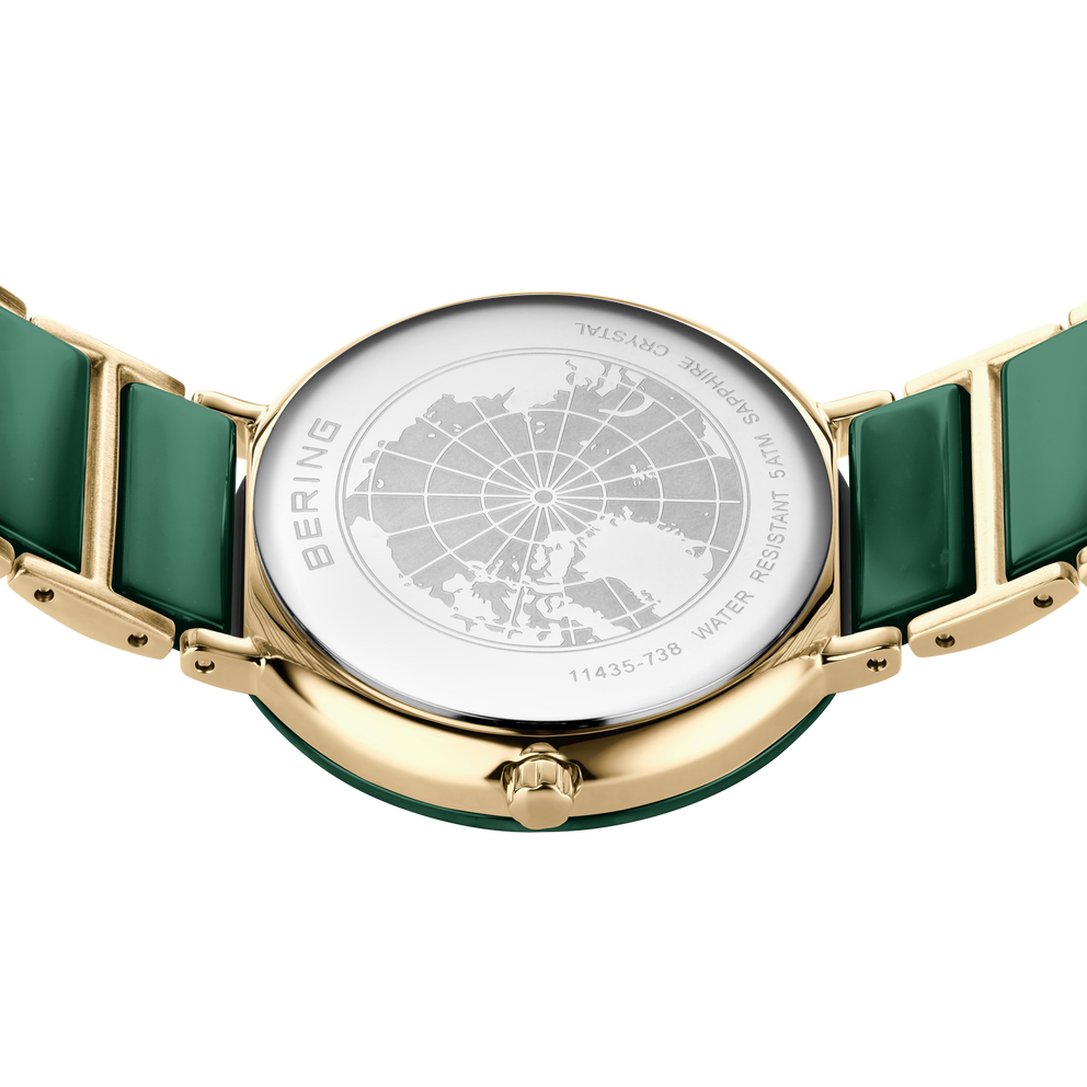 Orologio color oro con cinturino verde, visto dall'alto con cassa trasparente che rivela il quadrante mappamondo.