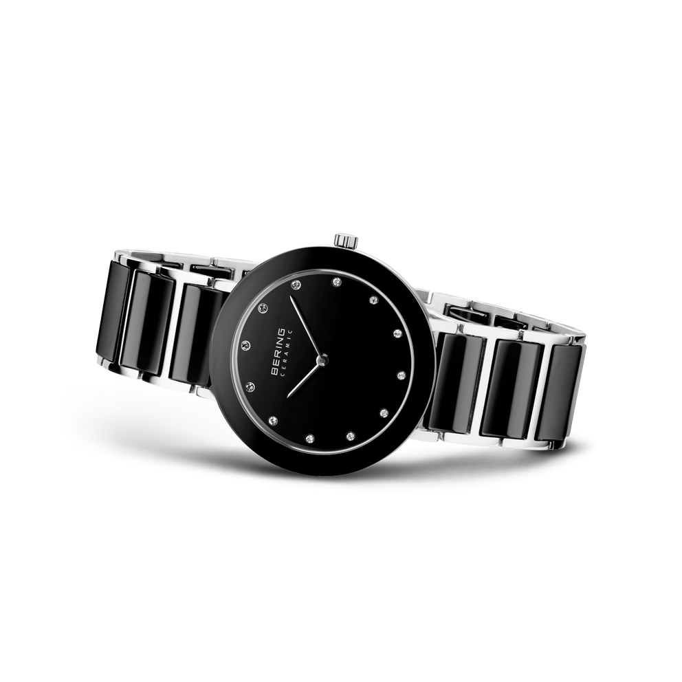 Orologio nero da angolazione tre-quarti, indici bianchi sul quadrante, cinturino metallo rigato argento-nero