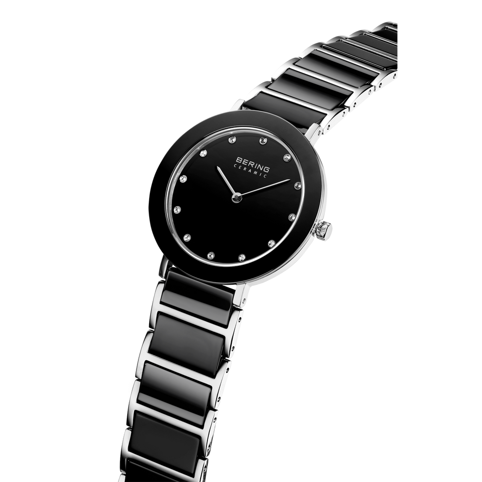 Orologio BERING con quadrante nero, marcatori e lancette bianchi, fotografato ad angolo con cinturino nero-argento.