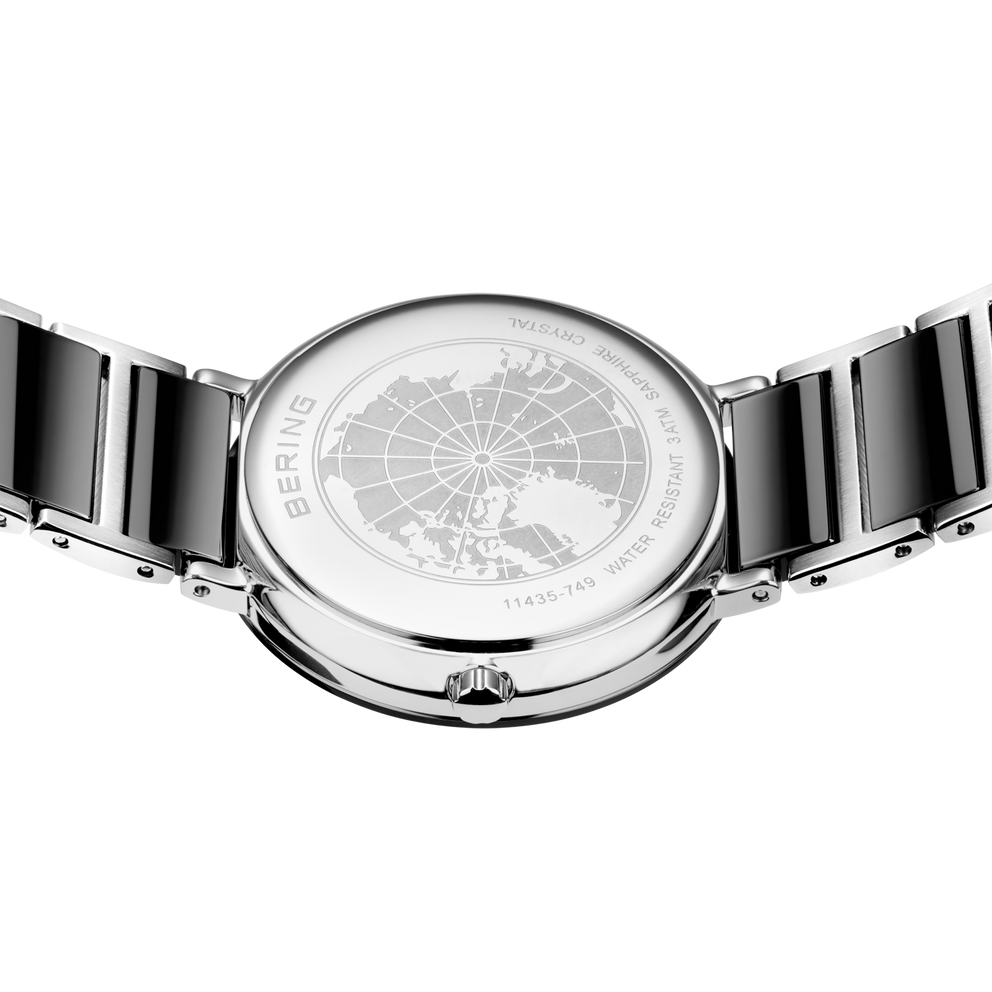 Orologio da polso con braccialetto nero e quadrante con motivo globo, visto dall'alto.