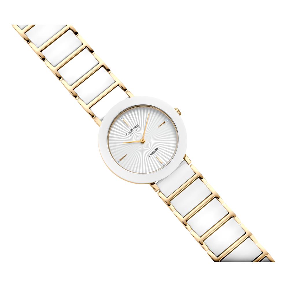 Round watch with white dial, gold-toned hands and mesh band, shown at diagonal angle