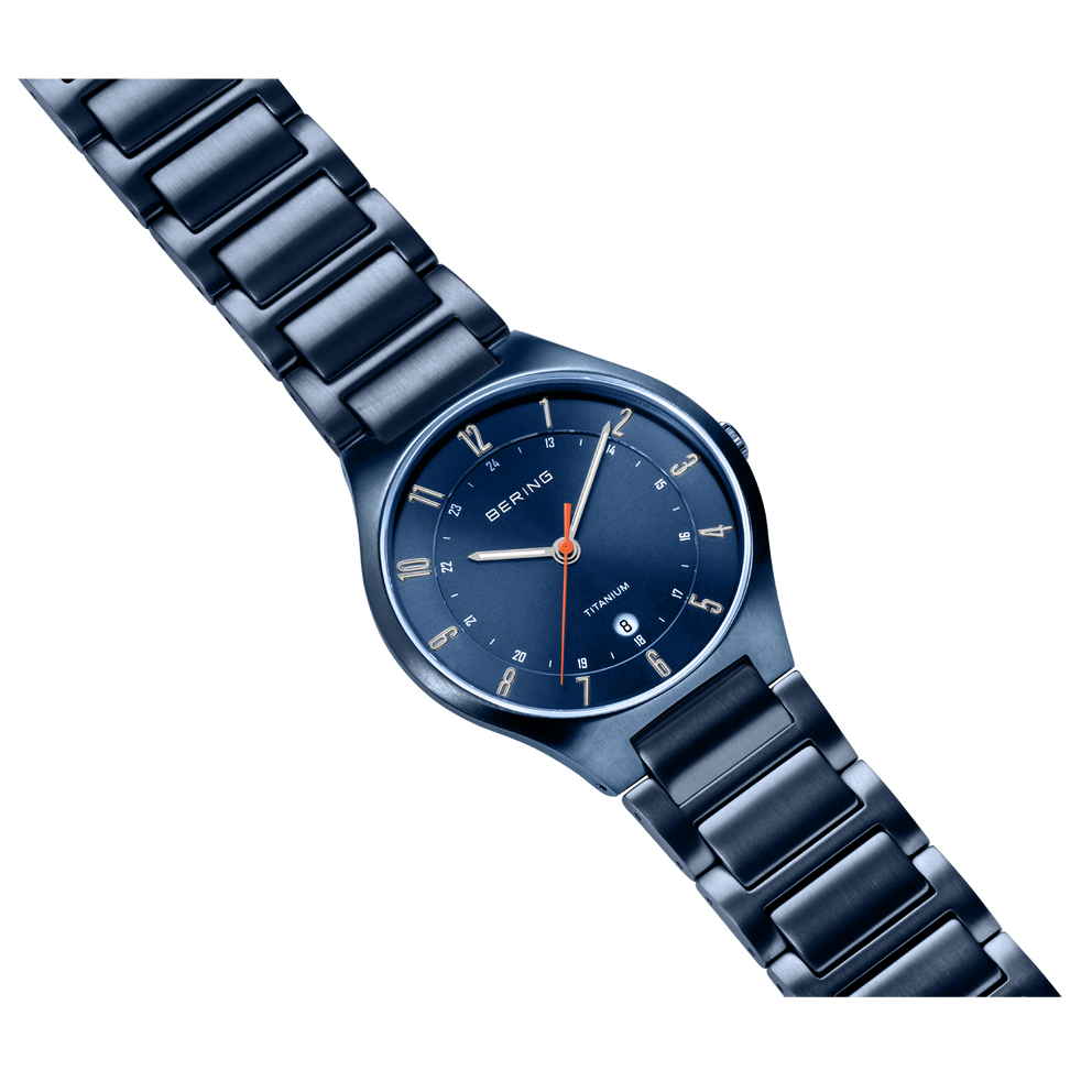 Navy metal wristwatch displayed diagonally with full bracelet visible, white hour markers and red accent hands.
