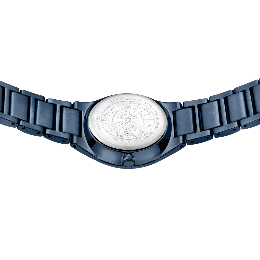 Watch face with white textured dial and dark blue segmented metal bracelet, viewed from above
