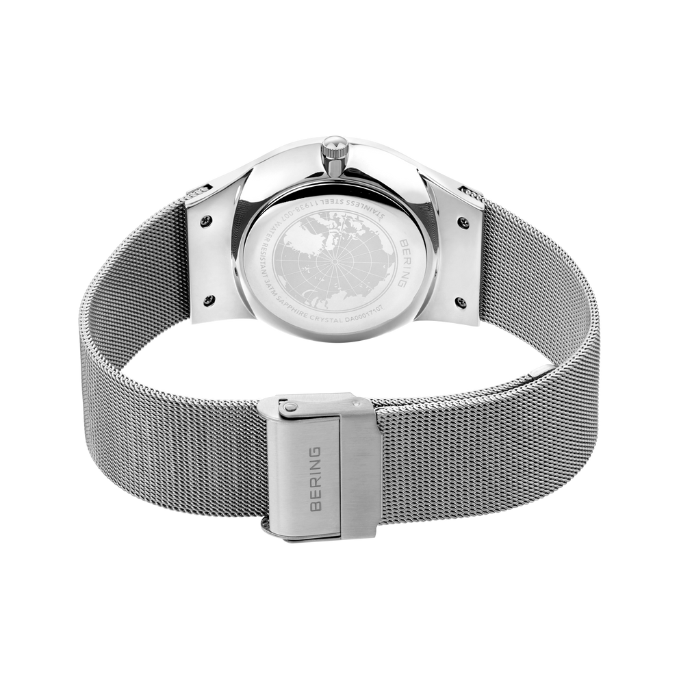 Reloj plateado con fondo de caja transparente, mecanismo visible y correa malla a juego con cierre BERING.