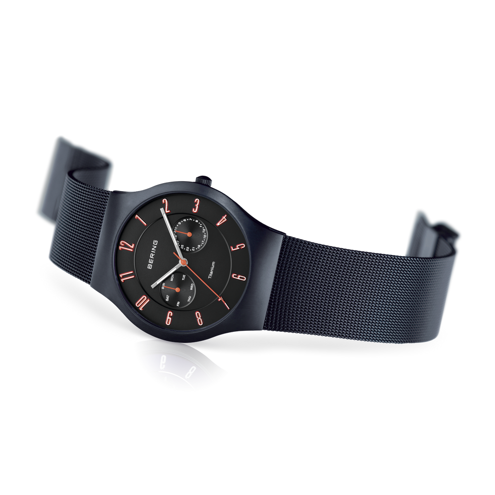 Montre BERING vue de côté, cadran noir avec marqueurs or rose, bracelet maille bleu foncé