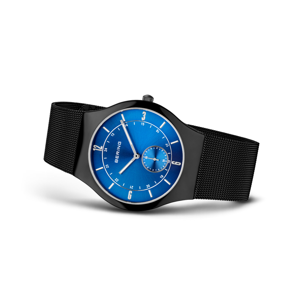 BERING wristwatch with blue dial, white indices, and subdial, black mesh band, angled view