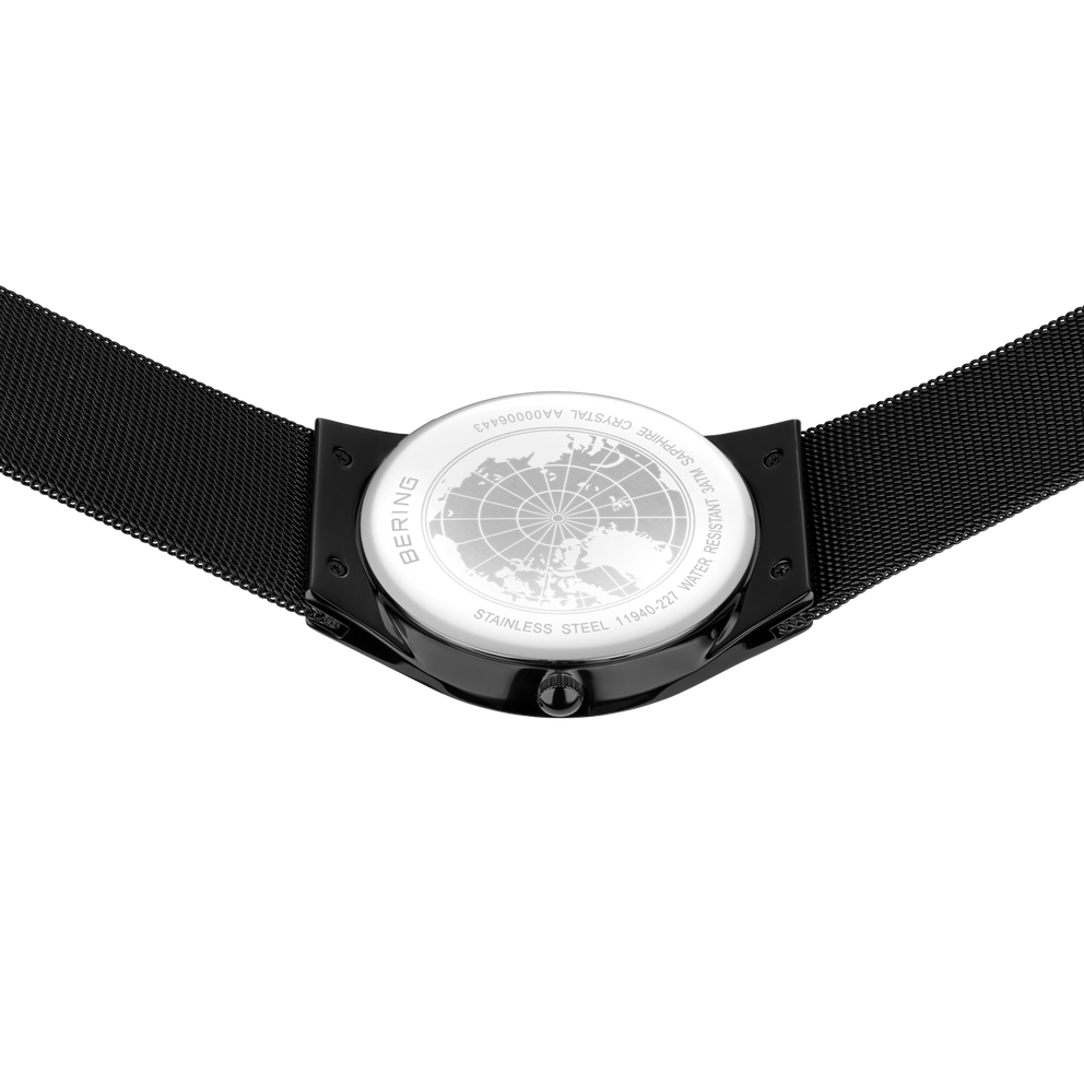 Wristwatch with round dial featuring engraved world map pattern, viewed from above with black textile strap visible on both sides.