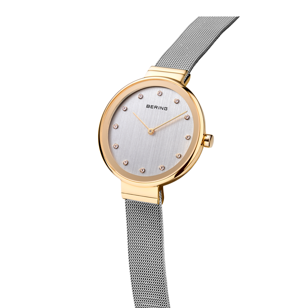 Gekantelde weergave van goudkleurig polshorloge met uitgestrekt meshband, rond horloge en lichte wijzerplaat.