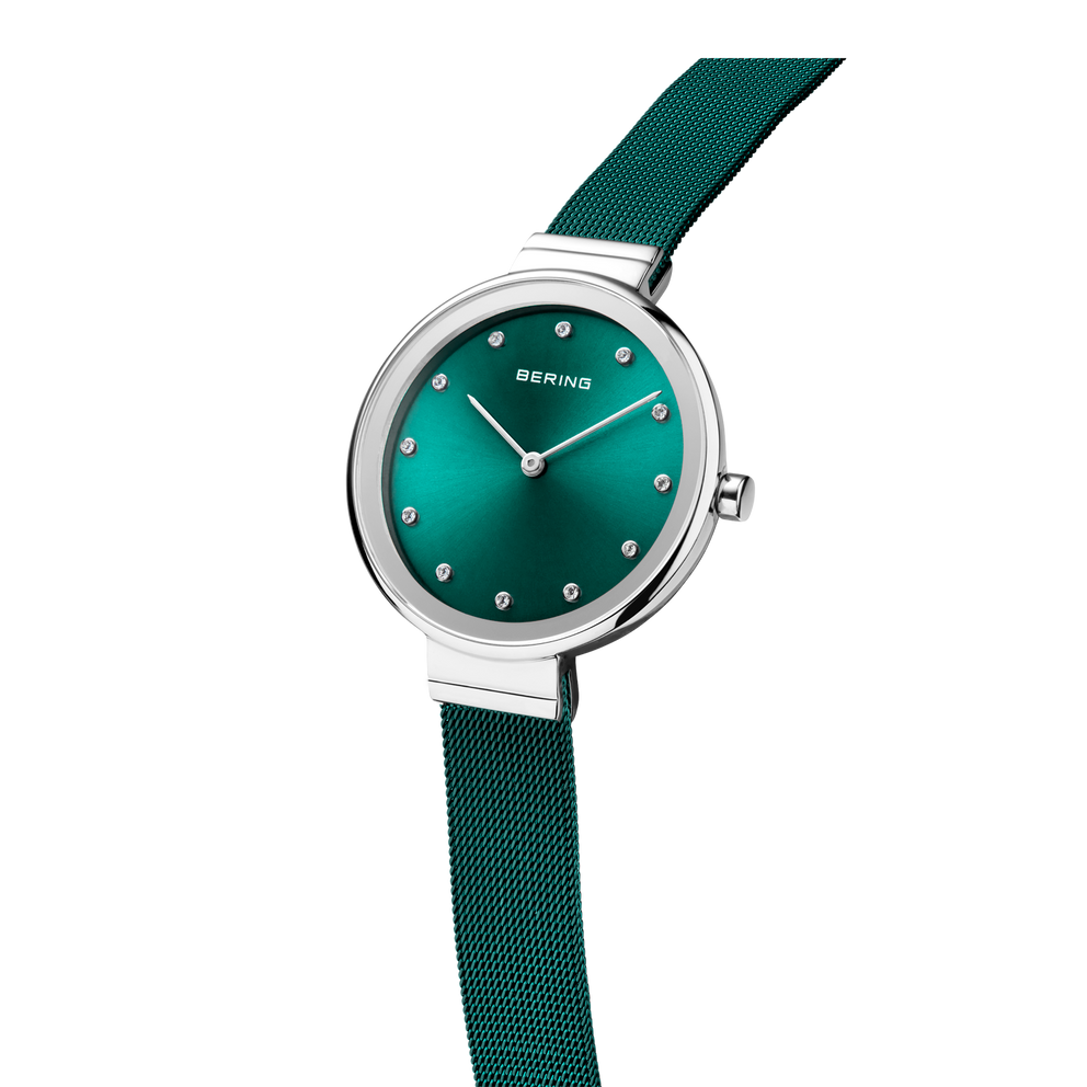 BERING watch with teal dial, silver case, minimalist hour markers, and dark teal textile strap.