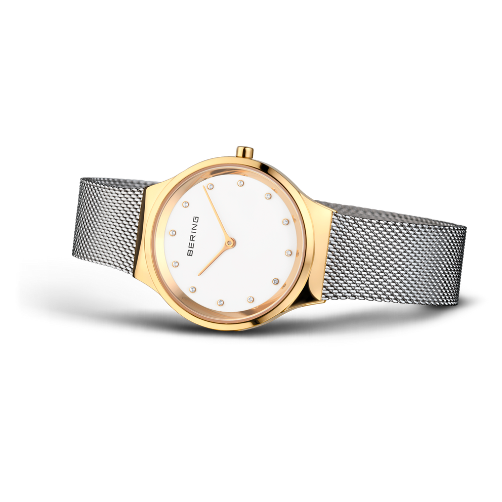 Gold-toned round watch with white dial, minimal hour markers, grey mesh strap, three-quarter view
