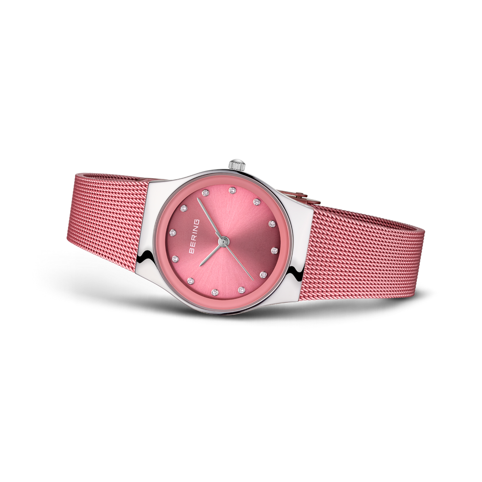 Round pink wristwatch with mesh band, angled three-quarter view