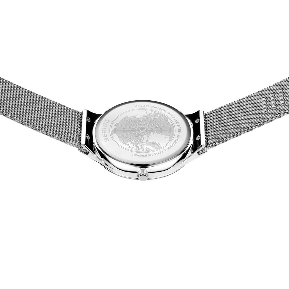 Montre ronde à cadran globe, boîtier chromé poli et bracelet mailles vues de dessus.