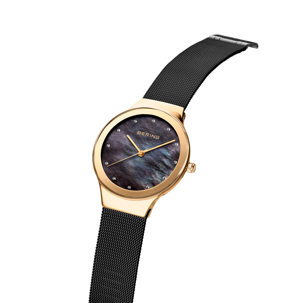 BERING wristwatch with rose-gold case, dark blue dial, and black mesh strap, shown at three-quarter angle.
