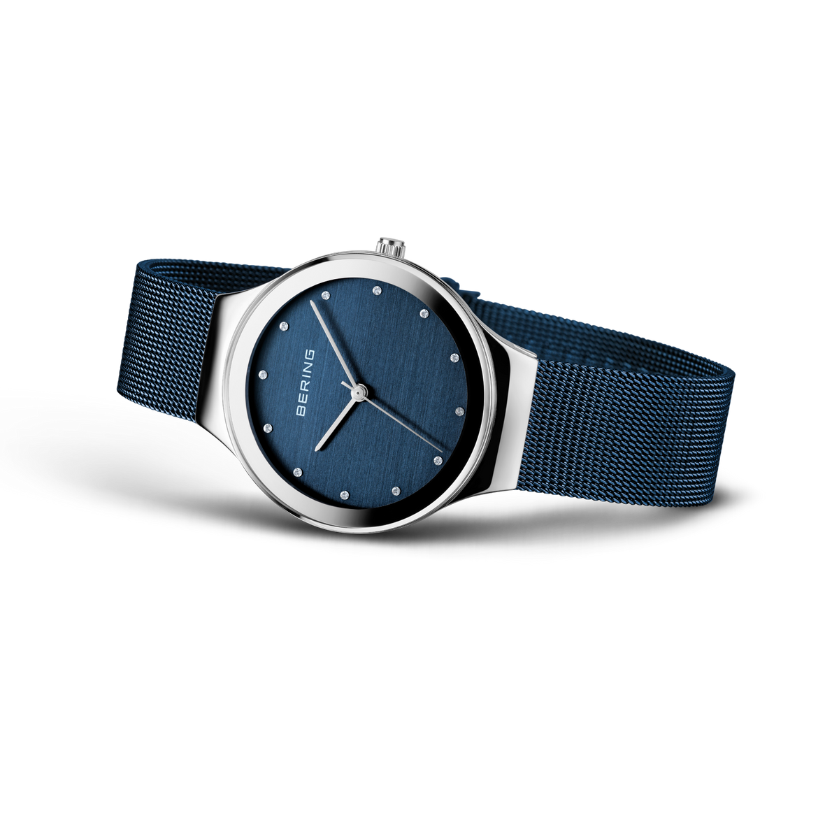 Wristwatch displayed at an angle, dark blue mesh band extended, showing navy dial and silver-tone case.