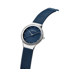 BERING wristwatch with silver case, dark blue dial, and matching mesh band, tilted to show band texture and side profile.