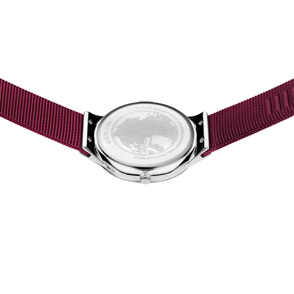 Achterkant van rond zilverkleurig horloge met donkerrood stofbandje, van bovenaf gefotografeerd