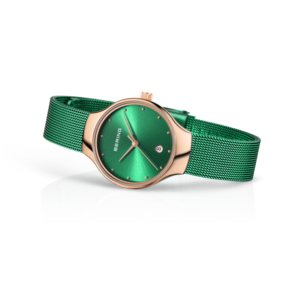 Montre BERING en vue trois-quarts montrant le boîtier rose doré, le bracelet maille verte et le cadran