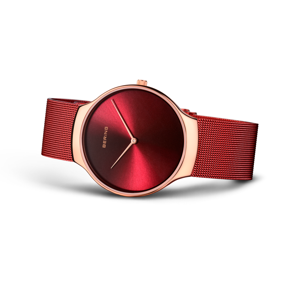 BERING Charity wristwatch with deep red dial and red mesh band, shown at an angle.