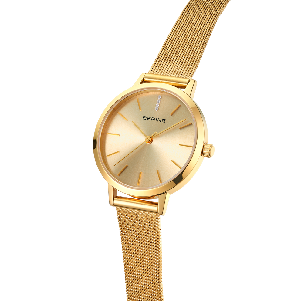 BERING gold-tone wristwatch with round case and mesh band, three-quarter angle view.