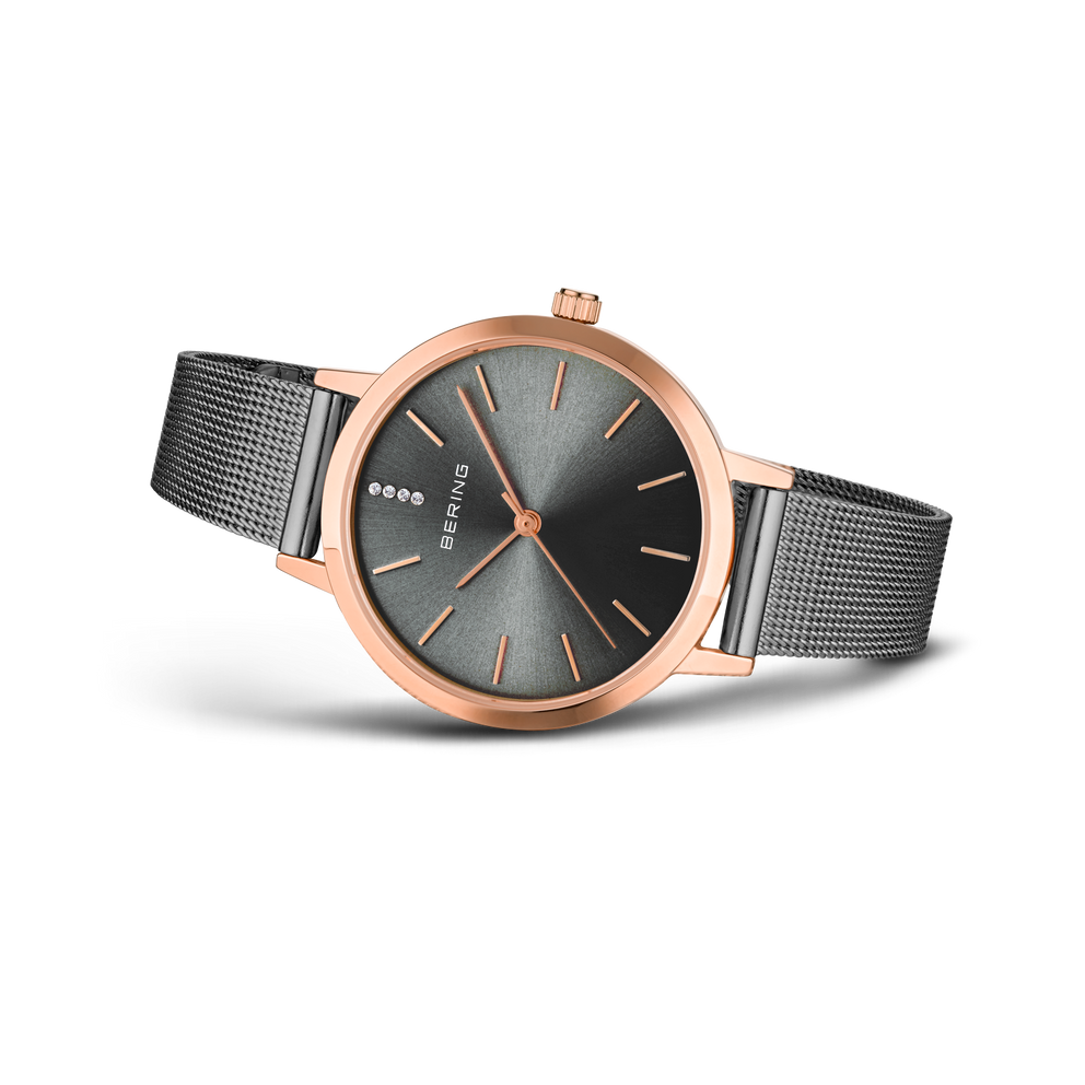 Montre or rose avec cadran gris foncé et bracelet maille, vue oblique