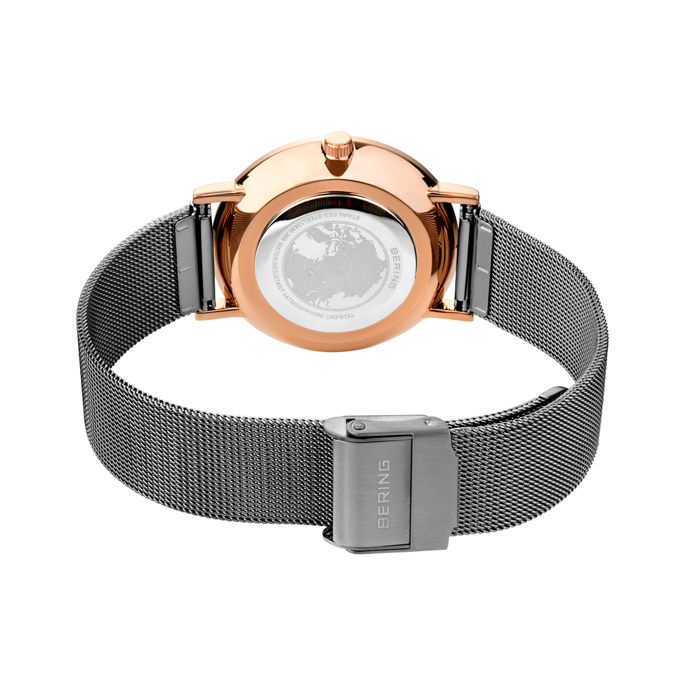 Rose gold watch case with gray mesh strap and magnetic clasp, viewed from the back