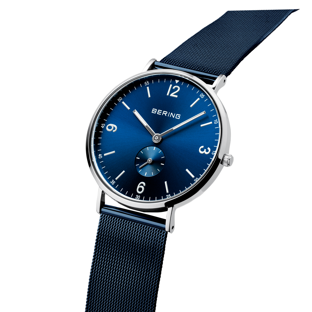 BERING watch with blue dial and silver-tone round case, dark blue fabric strap, angled view.