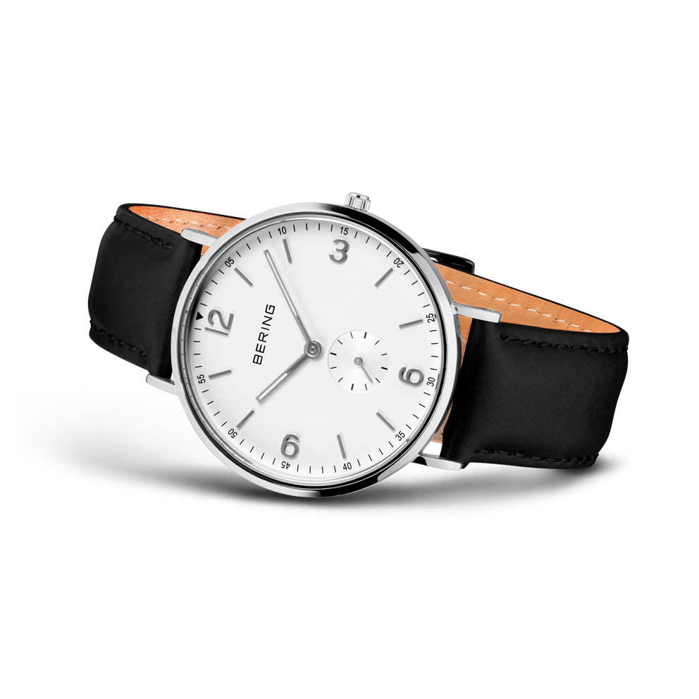 Montre BERING en vue trois quarts. Cadran blanc avec chiffres arabes, boîtier rond poli, bracelet cuir noir doublé beige.