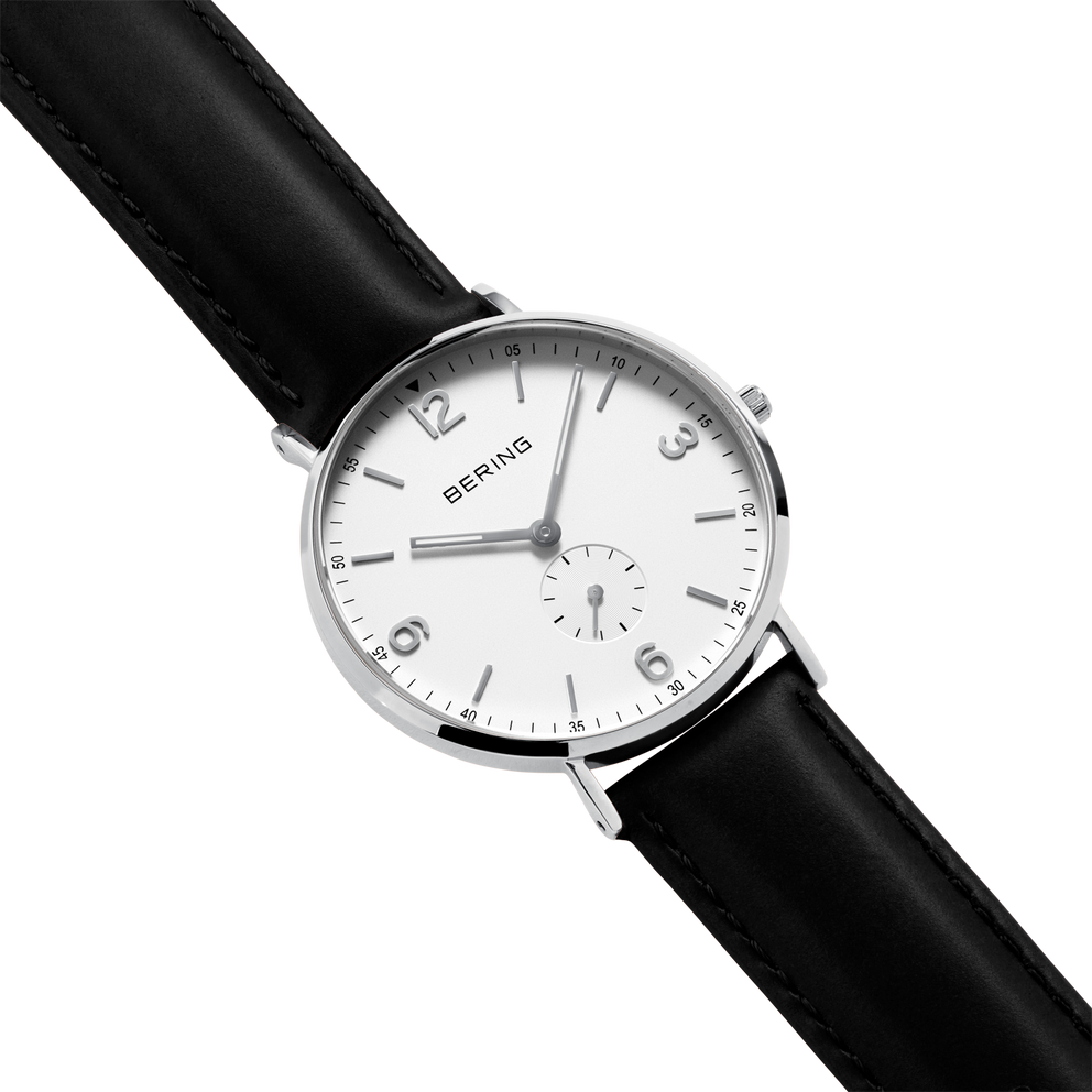 Montre au boîtier argenté, cadran blanc avec chiffres arabes, marquage BERING et bracelet noir en cuir, vue en angle.