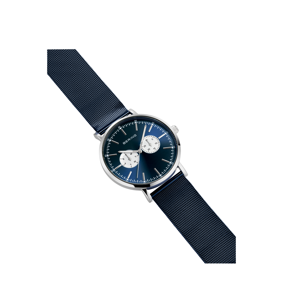 BERING-horloge met donkerblauwe wijzerplaat en twee chronograaftellers, diagonaal op marineblauw textielarmband.