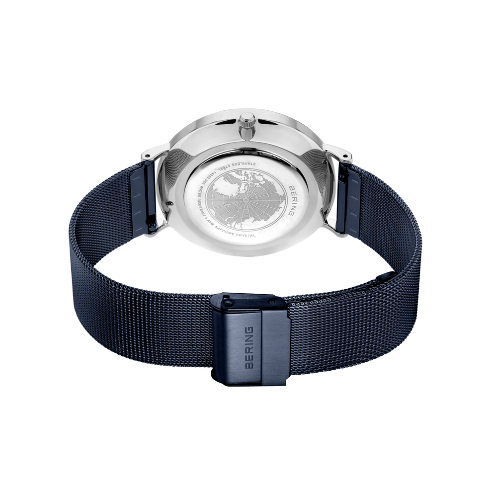 Back view of wristwatch with silver stainless steel case and dark blue mesh band, crown visible at top.
