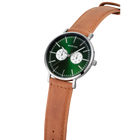 Reloj con esfera verde oscura, subdiales blancos, caja plateada y correa cuero marrón en ángulo.