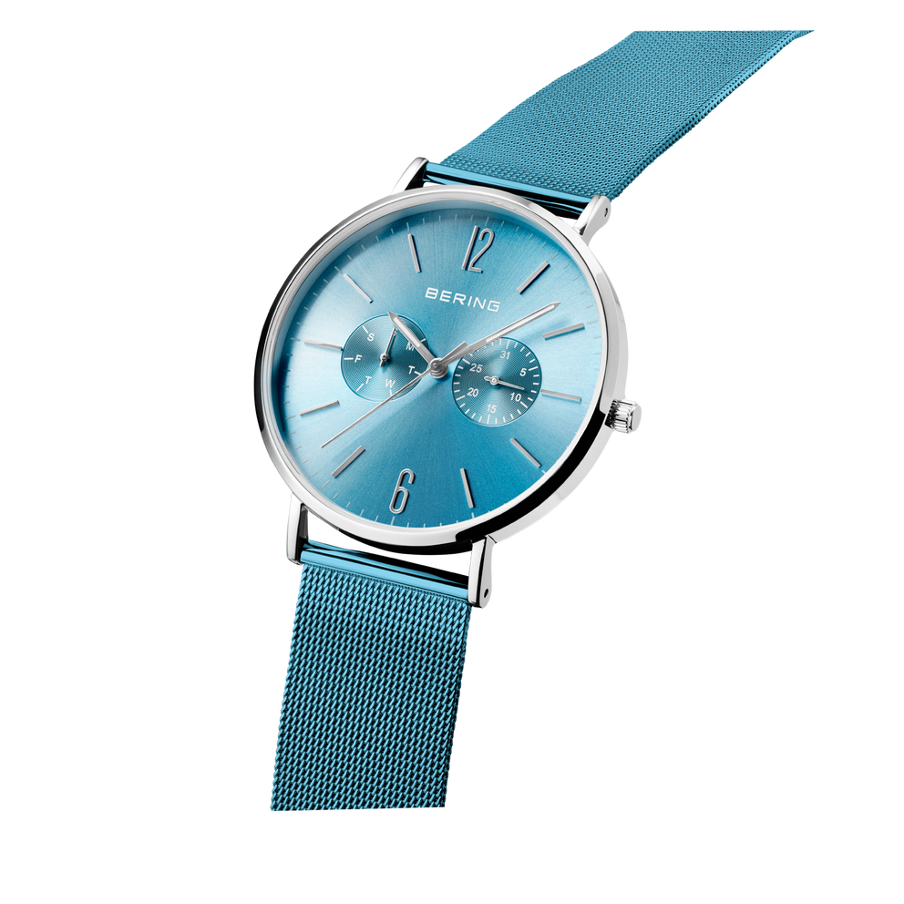 BERING watch with turquoise dial, silver case, and blue mesh band, tilted to display the bracelet.