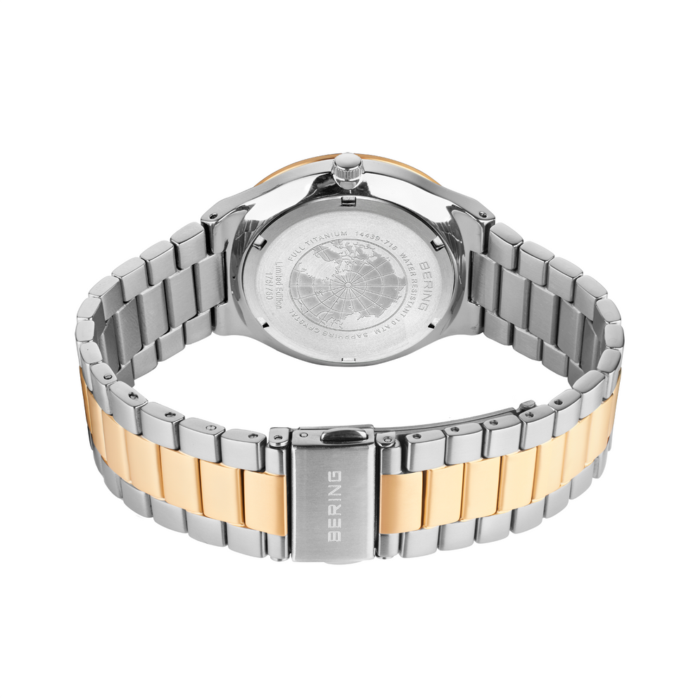Vista trasera del reloj con pulsera metalizada en plata y oro, con diseño de eslabones y tapa trasera grabada.